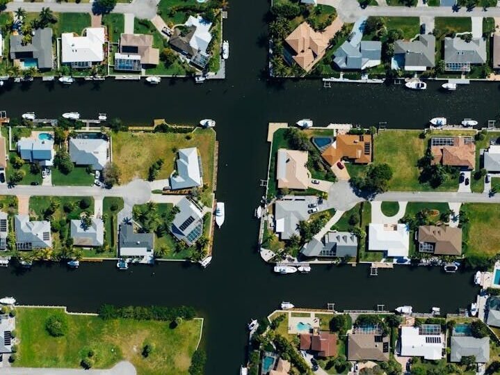 Drone shot of suburban canal-side homes arranged neatly with clear water channels.